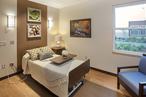 Resident room with nicely made bed and large window.